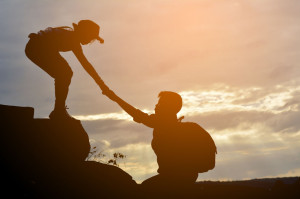 71271530 - silhouette of girl helps a boy on mountain at the sky sunset