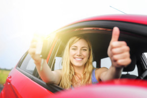 43474446 - happy woman in red car showing thumb up and key.