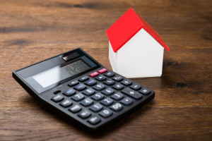 41236411 - close-up of miniature house with calculator on wooden table