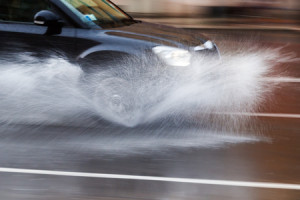 52580612 - driving car on a wet street with splashing water in motion blur