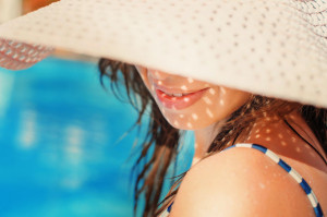 43151374 - beautiful girl in a hat relaxing near a swimming pool.