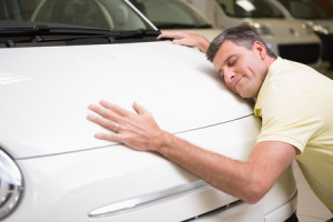 36413980 - smiling man hugging a white car at new car showroom