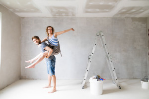 84759407 - young couple painting walls in their new house.