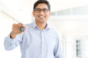 26537754 - young asian indian estate agent or salesman showing a key