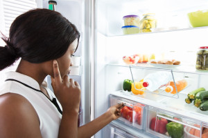 92339658 - young woman looking in fridge at kitchen