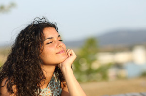 44694898 - woman relaxing and enjoying the sun in a warmth park at sunset
