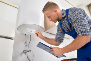 44591897 - male worker with clipboard adjusting temperature of water heater