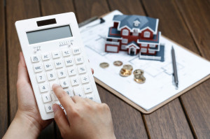 72280886 - a female hand operating a calculator in front of a villa house model