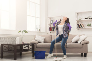 Happy woman cleaning home with mop and having fun