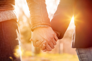 38774769 - closeup of loving couple holding hands while walking at sunset