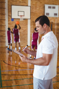 Basketball coach writing on clipboard