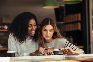 Friends sitting in a cafe looking at mobile phone