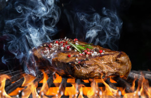 57548809 - beef steak on grill in fire with black background