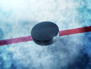 31998372 - hockey puck above the ice and red line with lens flare around puck.