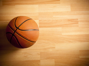 An official orange ball on a hardwood basketball court