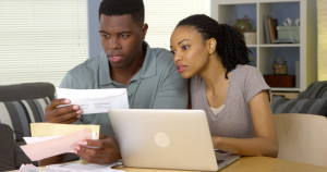 Serious young black couple paying bills online with laptop computer