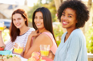 Three Female Friends Enjoying Meal At Outdoor Party