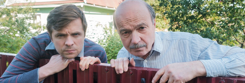 two caucasian men carefully watching over the fence.