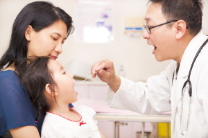 Pediatrician checking little girl throat