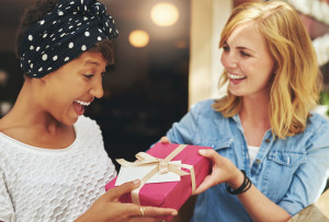 Young woman giving a friend a surprise gift