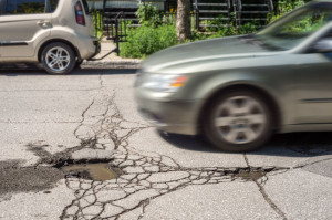 63153612 - large deep pothole with car approaching in montreal street, canada.