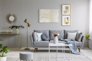 Real photo of a grey sofa with cushions and blanket standing in