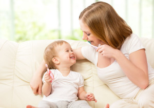 mother and daughter baby girl brushing their teeth together