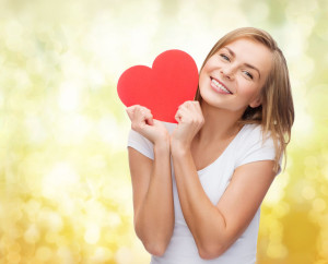 smiling woman in white t-shirt holding red heart