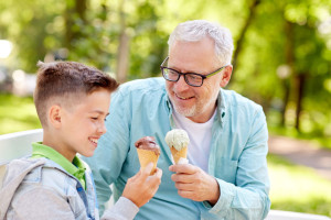 old man and boy eating ice cream at summer park