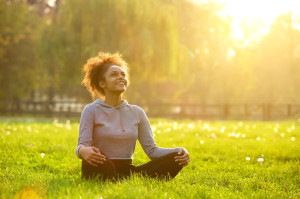 41009784 - happy young woman sitting outdoors in yoga position