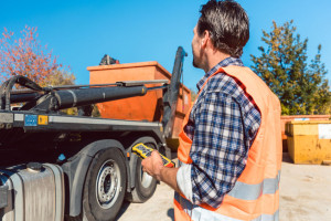 Worker on construction site unloading container for waste from truck