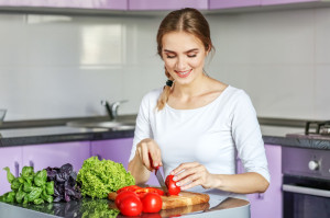 Young happy woman is preparing a delicious lunch in the kitchen.