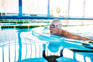 Senior man swimming in an indoor swimming pool.