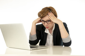 Attractive young business woman in glasses working on her computer stressed, tired and overwhelmed.