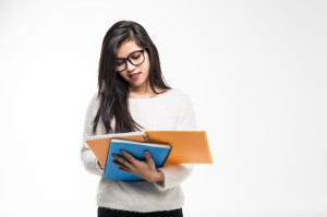 Portrait of attractive asian indian student woman standing holding reading a book with copy space over white background. Education test exam thinking concept