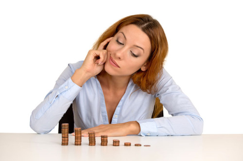business woman corporate executive sitting at table with growing stack of coins