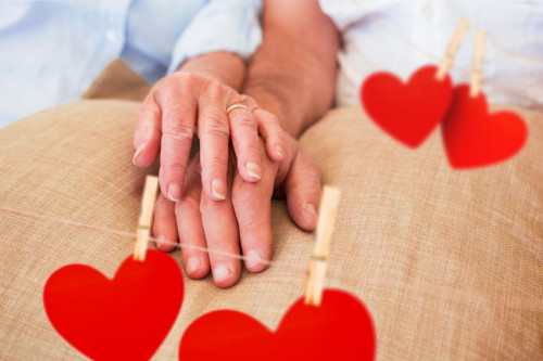 Hearts hanging on a line against retired couple holding hands
