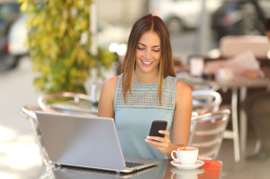 Entrepreneur working with a phone and laptop in a coffee shop