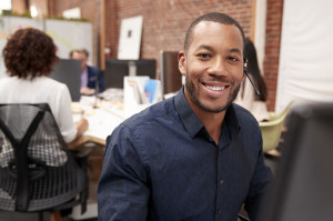 Portrait Of Male Customer Services Agent Working At Desk In Call Center