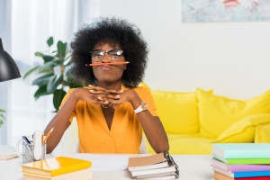 portrait of african american freelancer in eyeglasses with pencil at workplace at home office
