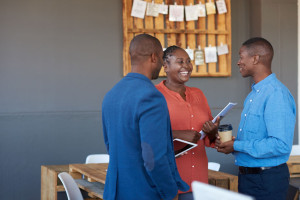 Three African work colleagues talking together in a moden office