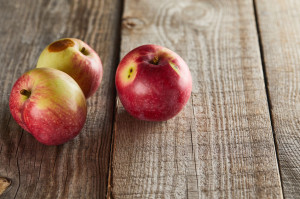 apples with small rotten spot on wooden surface