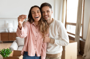 Happy couple holding key to new home on moving day