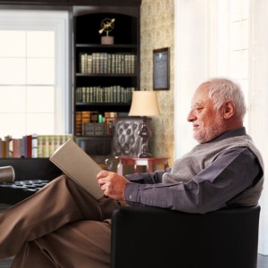 Elderly man reading book at study at home
