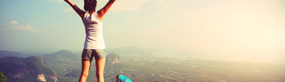 51473915 - cheering woman hiker open arms at mountain peak