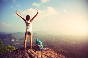 51473915 - cheering woman hiker open arms at mountain peak