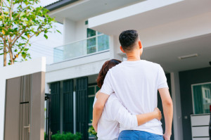 Asian family standing outside with their new house  and car carrying boxes