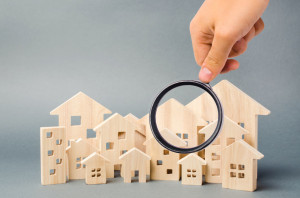 Wooden houses and magnifying glass. Property valuation. Home appraisal. Choice of location for the construction. House searching concept. Search for housing and apartments. Real estate