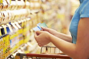 Woman In Grocery Aisle Of Supermarket With Coupons