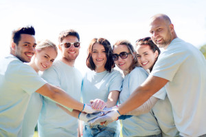 group of volunteers putting hands on top in park